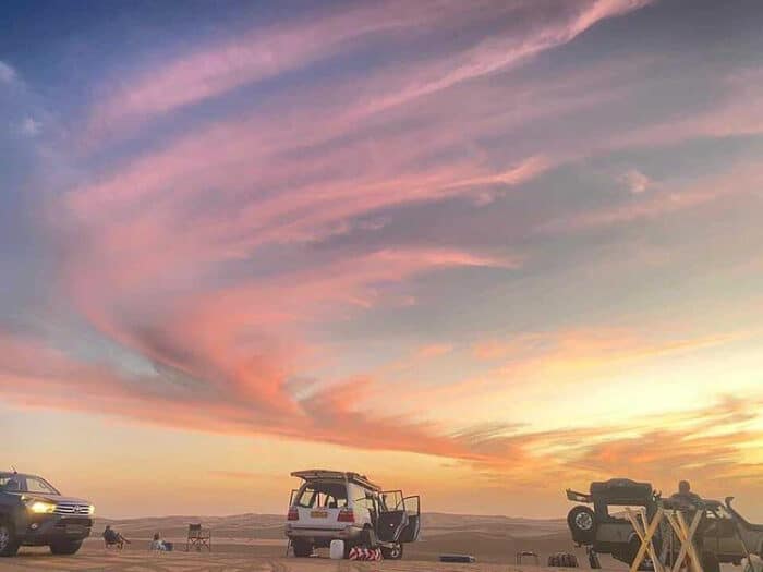 Three four wheel drives at sunset, Namib desert