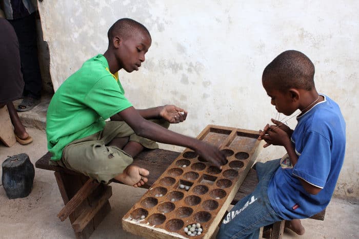 Children playing a traditional board game - Bao - in Lamu