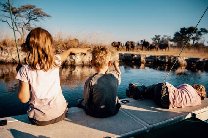Children observing elephants from a boat in Kwando