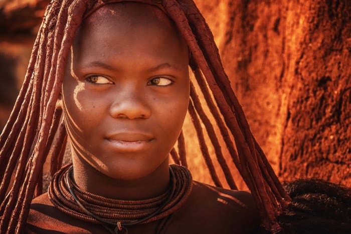 Young himba woman, wearing the traditional hairstyle, leather necklaces and red ochre paste on her skin