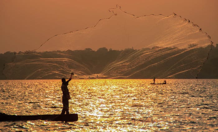 Local fisherman throwing his net at sunset, Lake Victoria