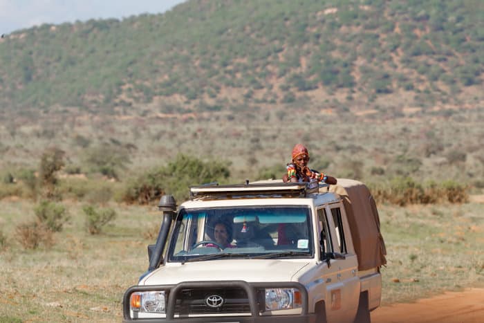 A Samburu safari guide looks out for animals from an open jeep