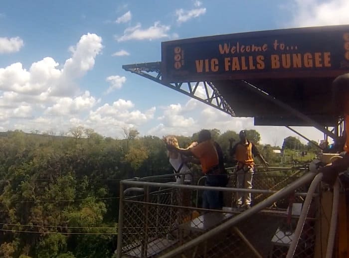 Raising arms at shoulder length before bungee jumping off Victoria Falls Bridge